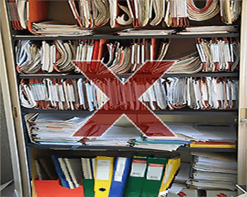 Classement de documents papier mal organisé Exemple d'armoire mal organisée : des piles de documents désordonnées, des dossiers suspendus surchargés et même cassés, des classeurs et des boites en désordre